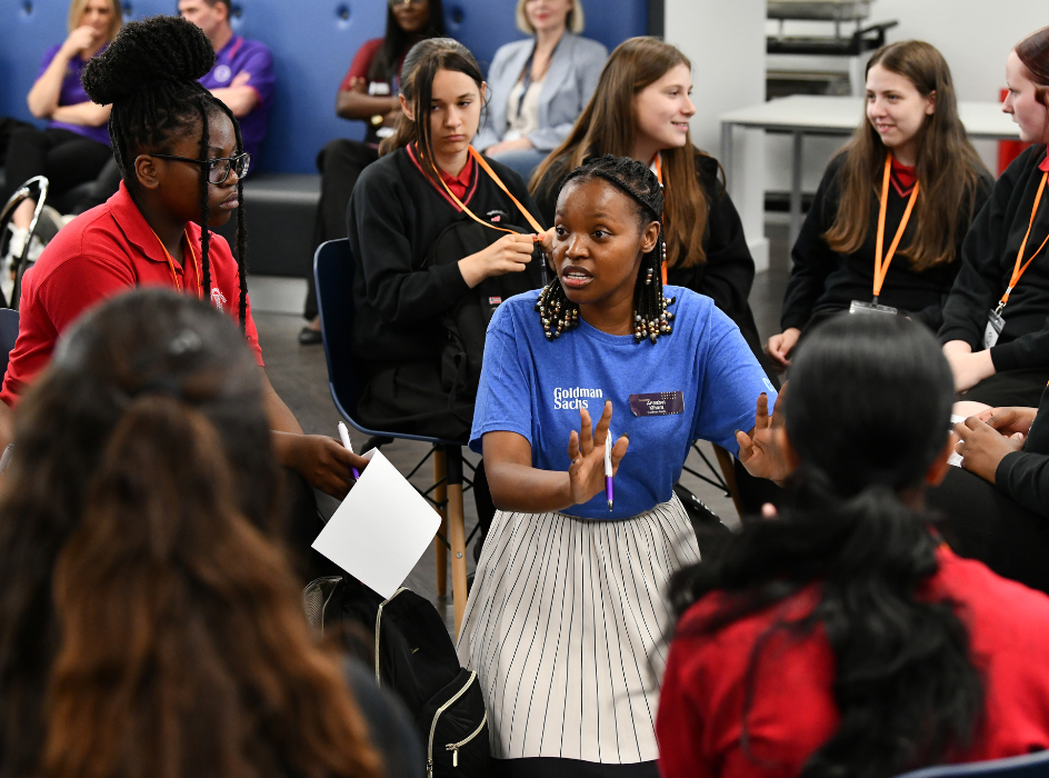 Students sit in a circle with a volunteer sitting in the middle